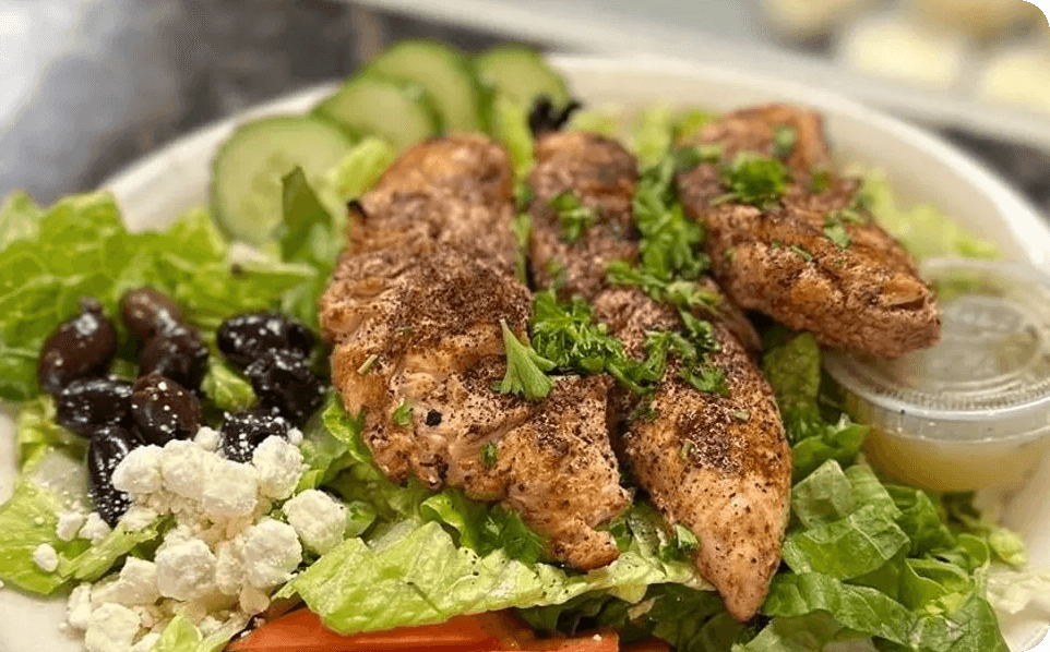 A salad with chicken and feta cheese on top.